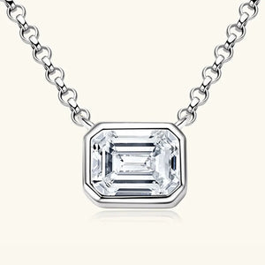 Silver necklace with emerald cut moissanite in gold bezel setting.