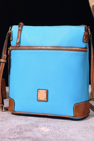 Pastel blue leather crossbody bag with brown trim and gold zipper.