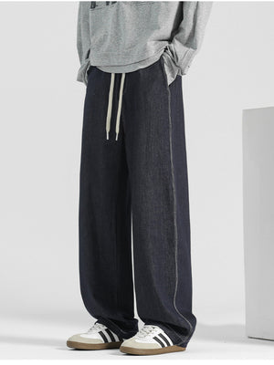 Men's dark blue wide-leg jeans with drawstring and contrast stitching.