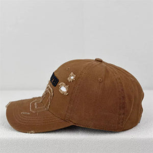Brown distressed baseball cap with embroidered patches and frayed details.