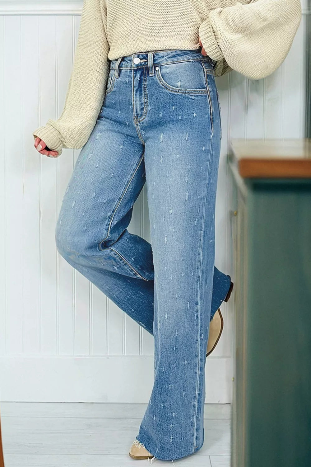 High-rise light wash denim jeans with distressed details and raw hem.