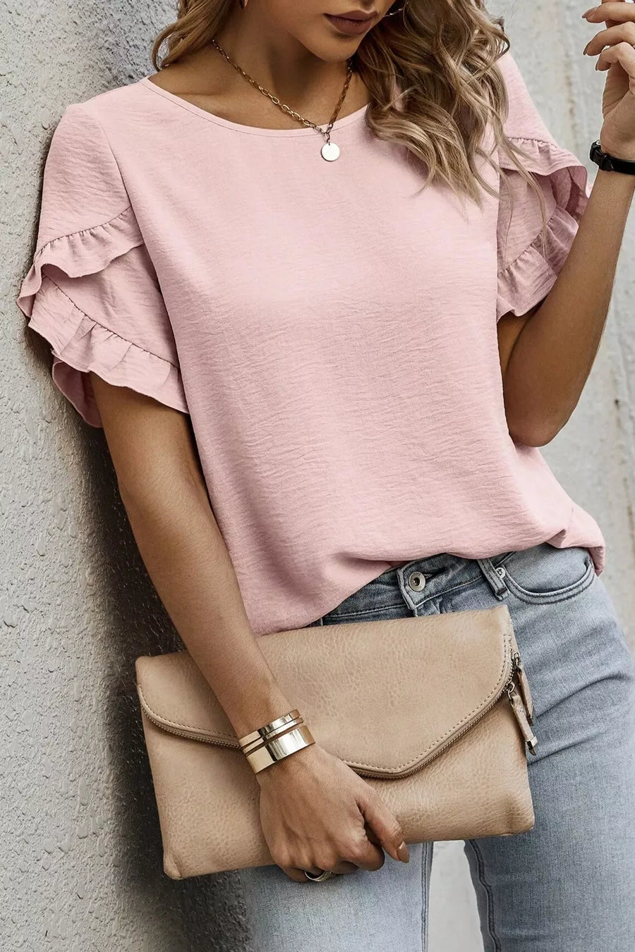 Blush pink polyester blouse with ruffle trim short sleeves and a textured finish.