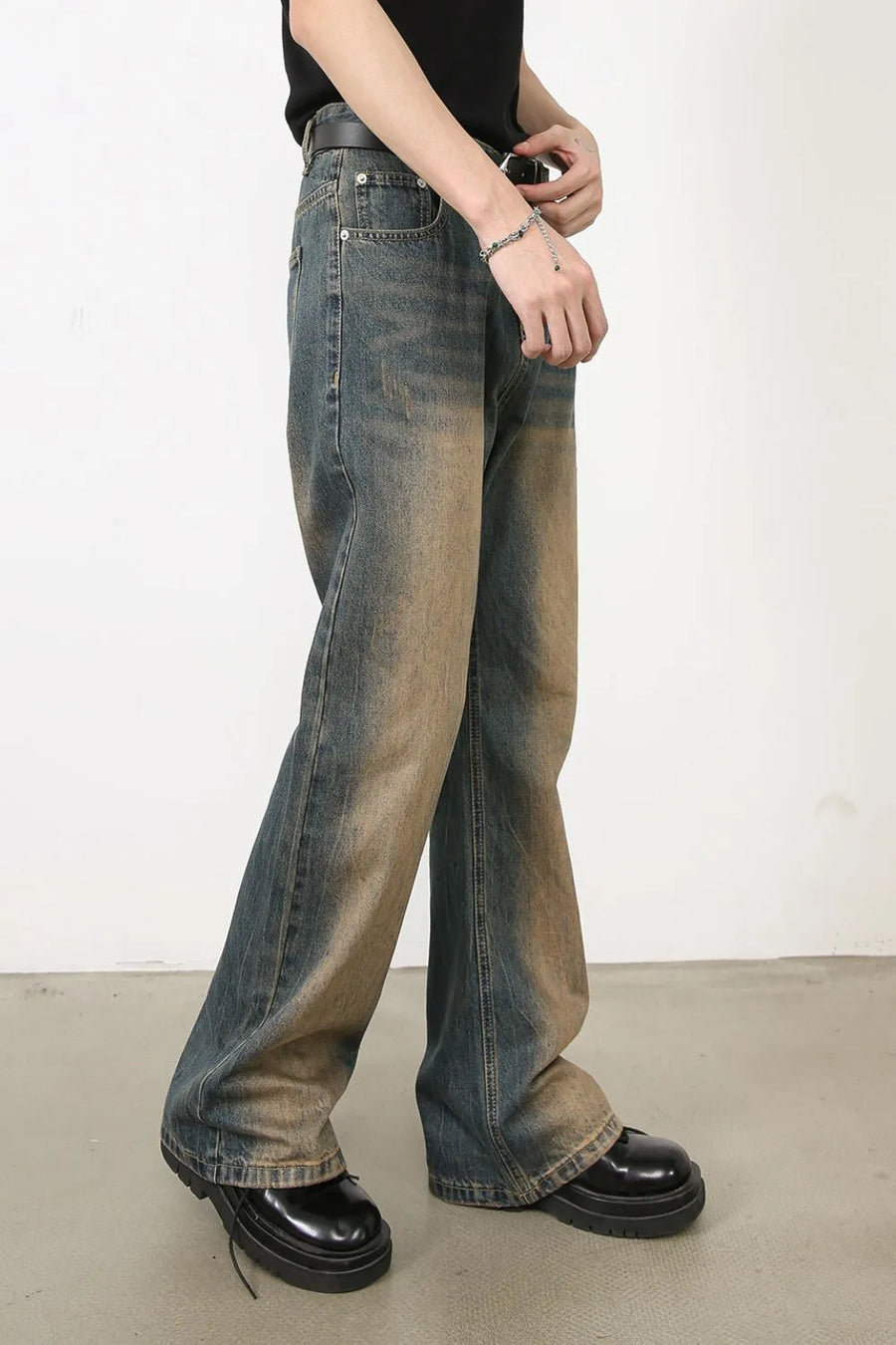 Faded wash bootcut denim jeans in medium color with a distressed look.