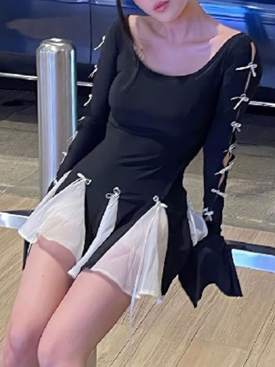 Black mini dress with long sleeves, bowknot details on sleeves and skirt, and sheer white inserts.