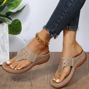 Beige laser-cut thong sandals with architectural detail and cushioned sole.