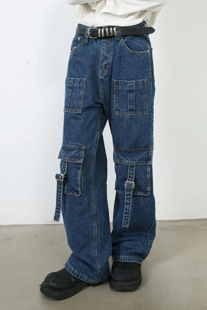 Medium wash denim cargo pants with buckle strap pockets and wide leg cut.