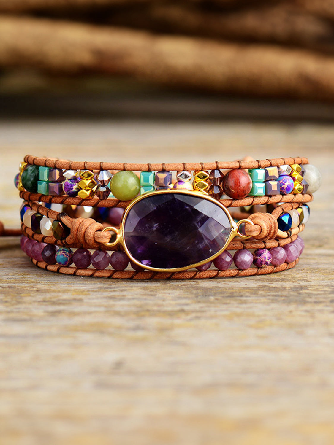 Wrapped amethyst and beaded bracelet with leather straps and gold accents.