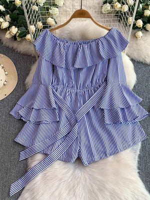 Blue striped off-shoulder romper with ruffles and a belted bow detail.