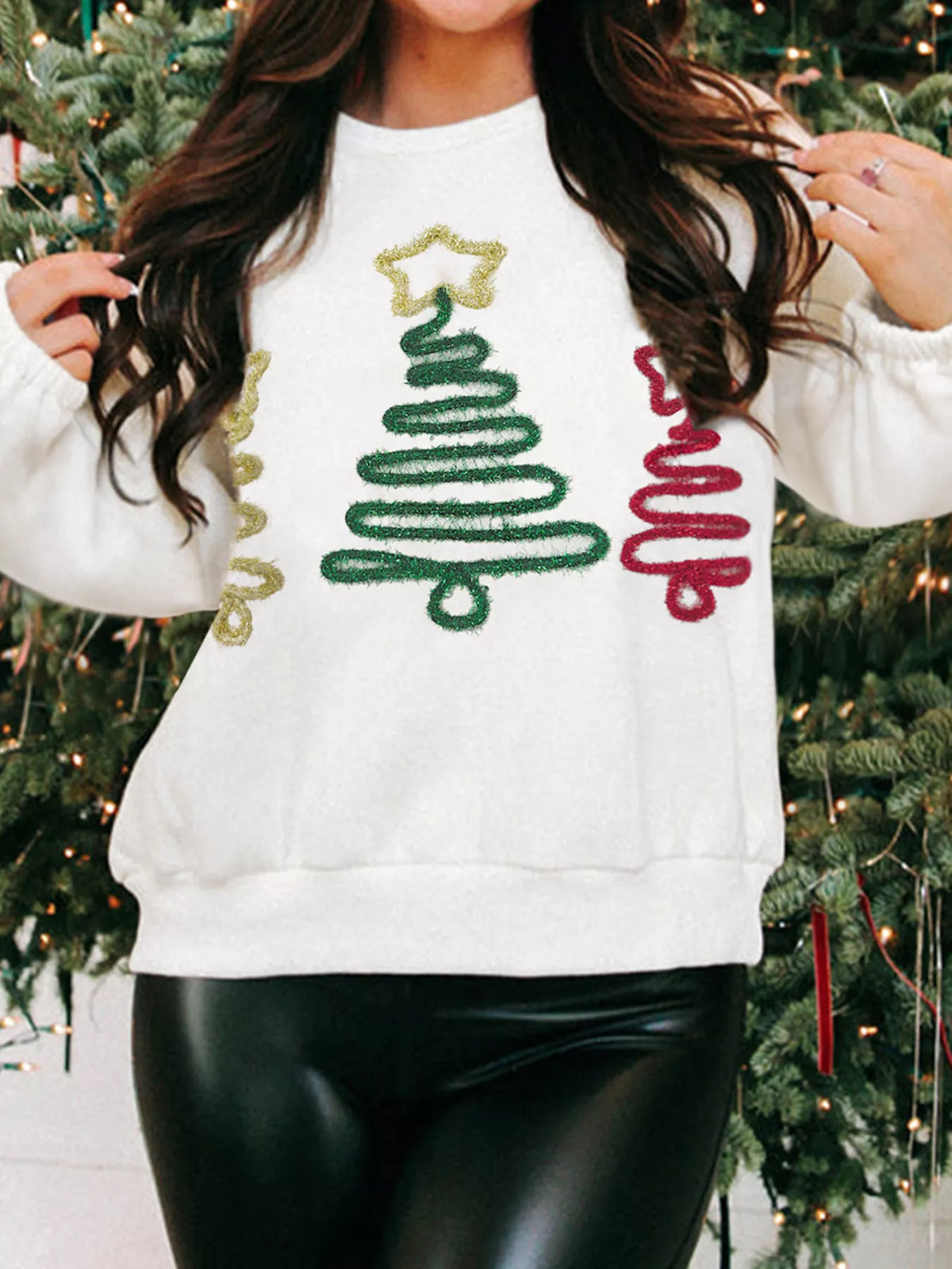 White crewneck sweatshirt with embroidered Christmas trees in green, red, and gold glitter.