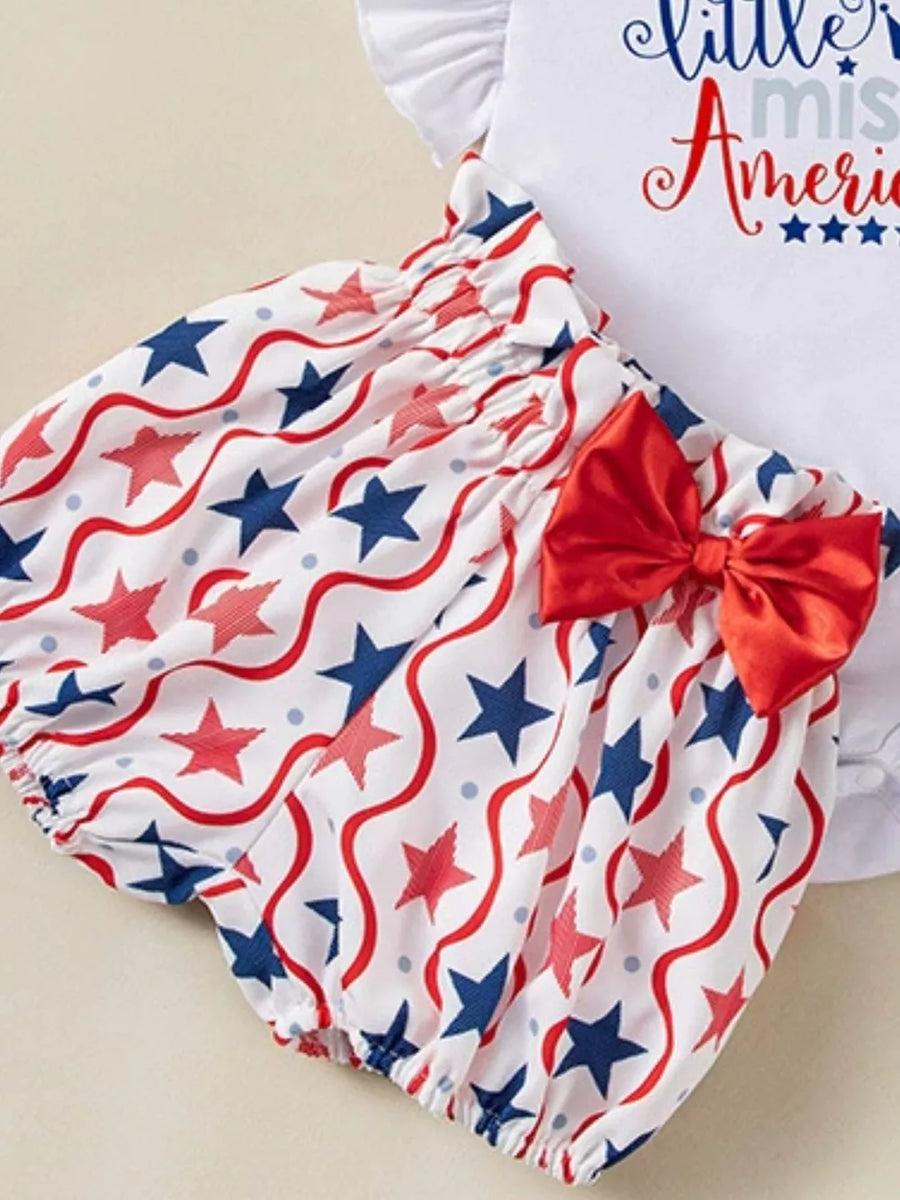 Baby girl outfit with red, white, and blue stars and wavy lines pattern, featuring bloomer shorts and a red bow.