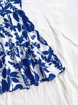 Vibrant floral mini dress with tiered ruffle hem and blue print on white fabric.