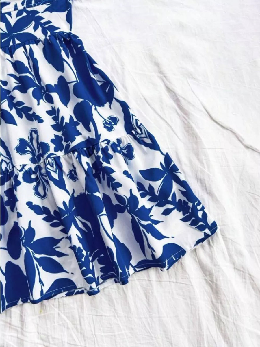Vibrant floral mini dress with tiered ruffle hem and blue print on white fabric.