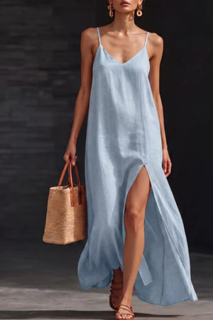 Light blue V-neck maxi dress with spaghetti straps and a high slit, styled with a straw tote bag.