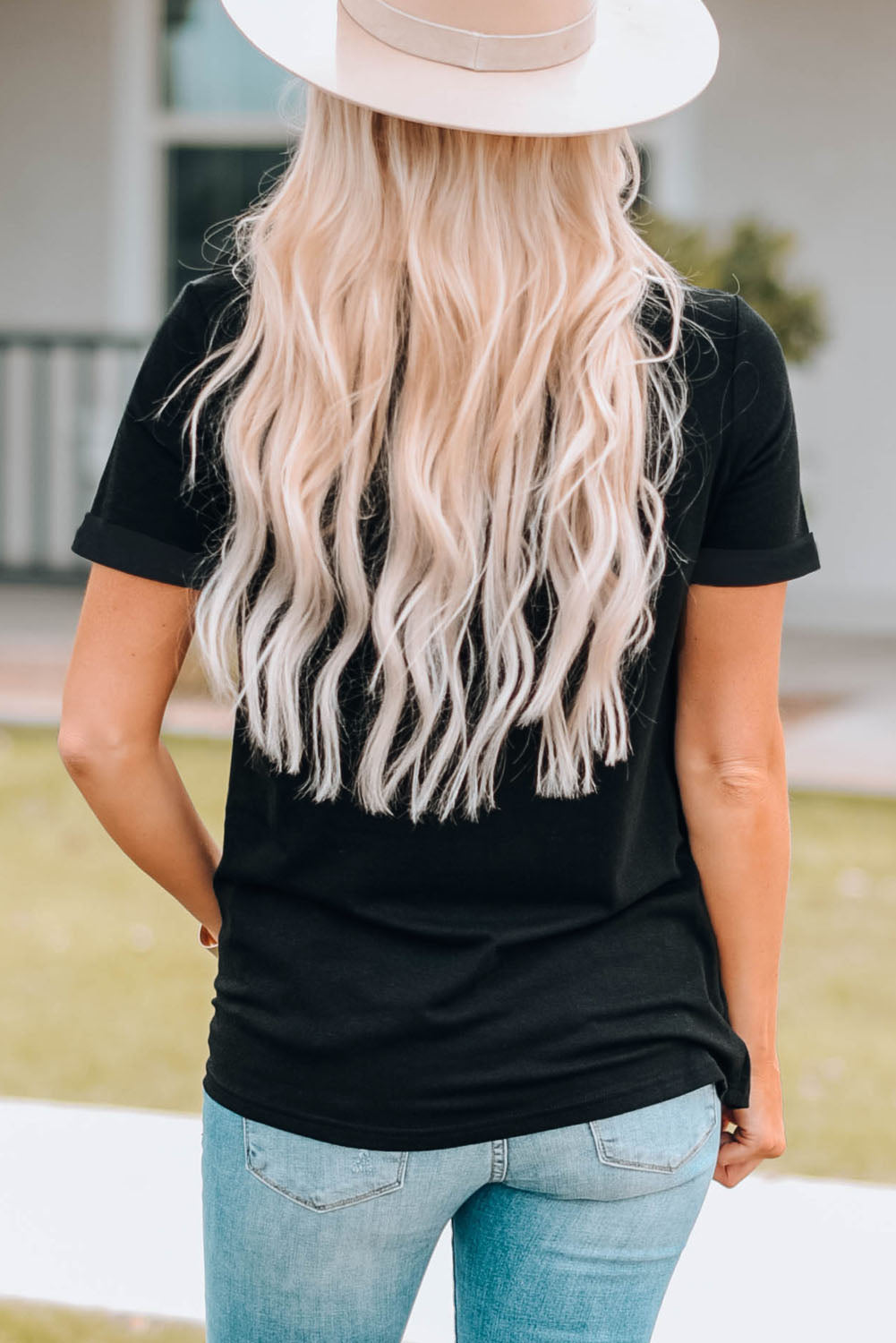 Black t-shirt with cuffed short sleeves and a relaxed fit, styled with jeans.