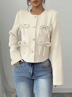 Cream textured jacket with bow details and pearl buttons, crew neck, long sleeves.