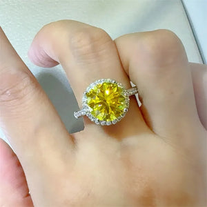 Sterling silver ring with a large yellow moissanite center stone and a halo of smaller stones.