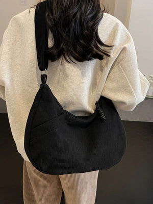 Black corduroy crescent shoulder bag with braided detail and adjustable strap.