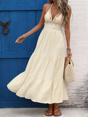 Cream halter neck maxi dress with tiered skirt and beaded trim.