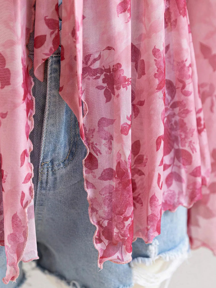 Pink floral chiffon blouse with ruffled hem detail.