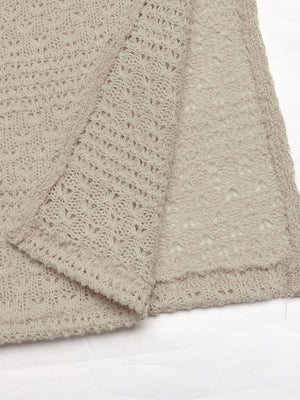 Beige knit maxi dress with cutout details and a slit, featuring a textured open-weave pattern.