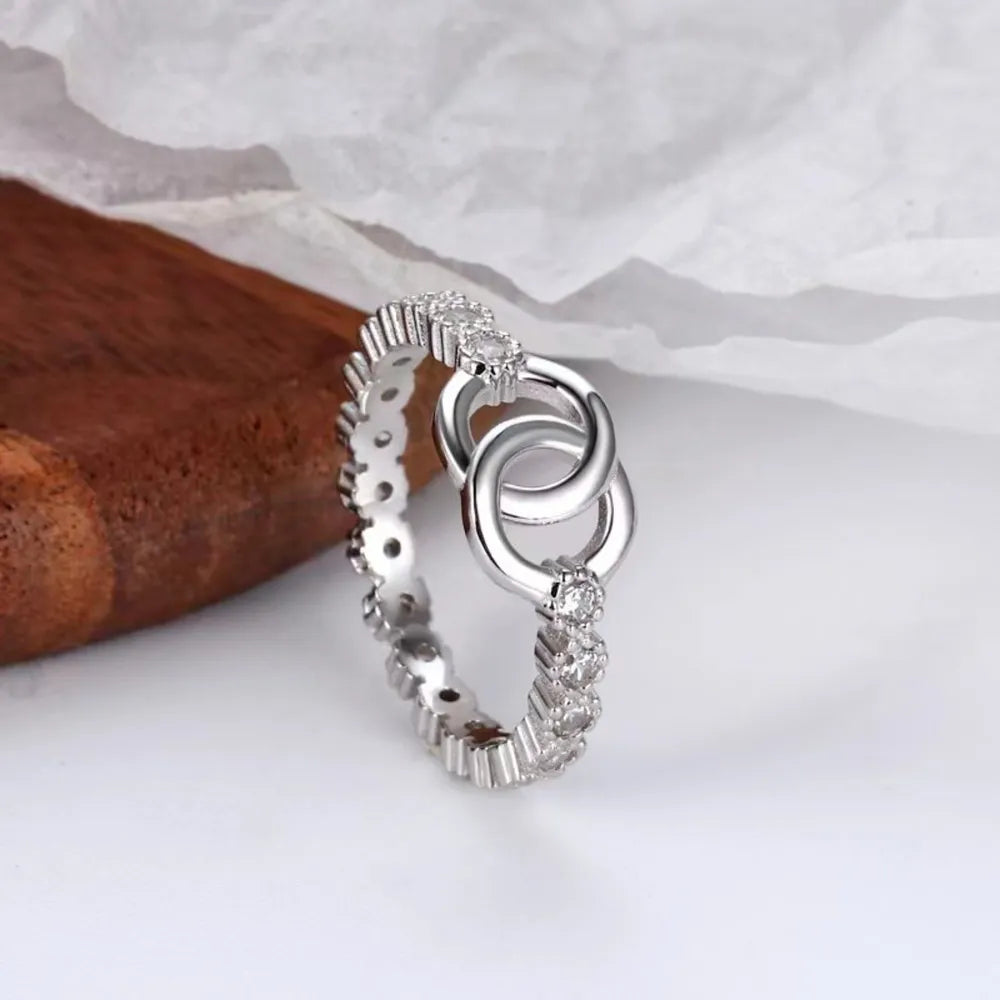 Silver interlocked pavé eternity ring with cubic zirconia accents.