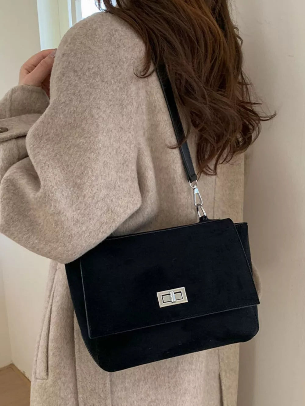 Black suede crossbody bag with flap closure and silver hardware.