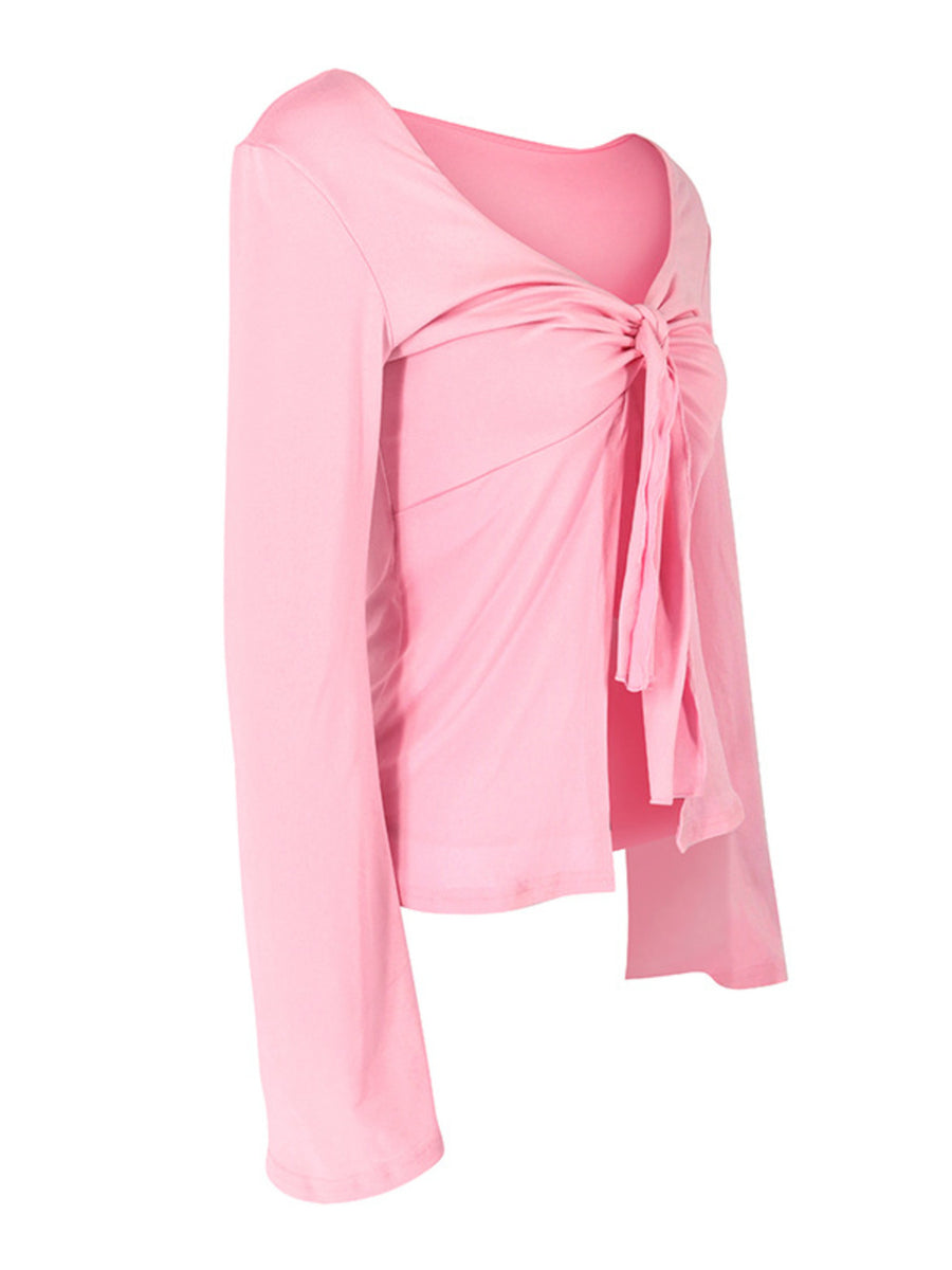 Pink tie-front long sleeve blouse with a V-neckline and draped front detail.