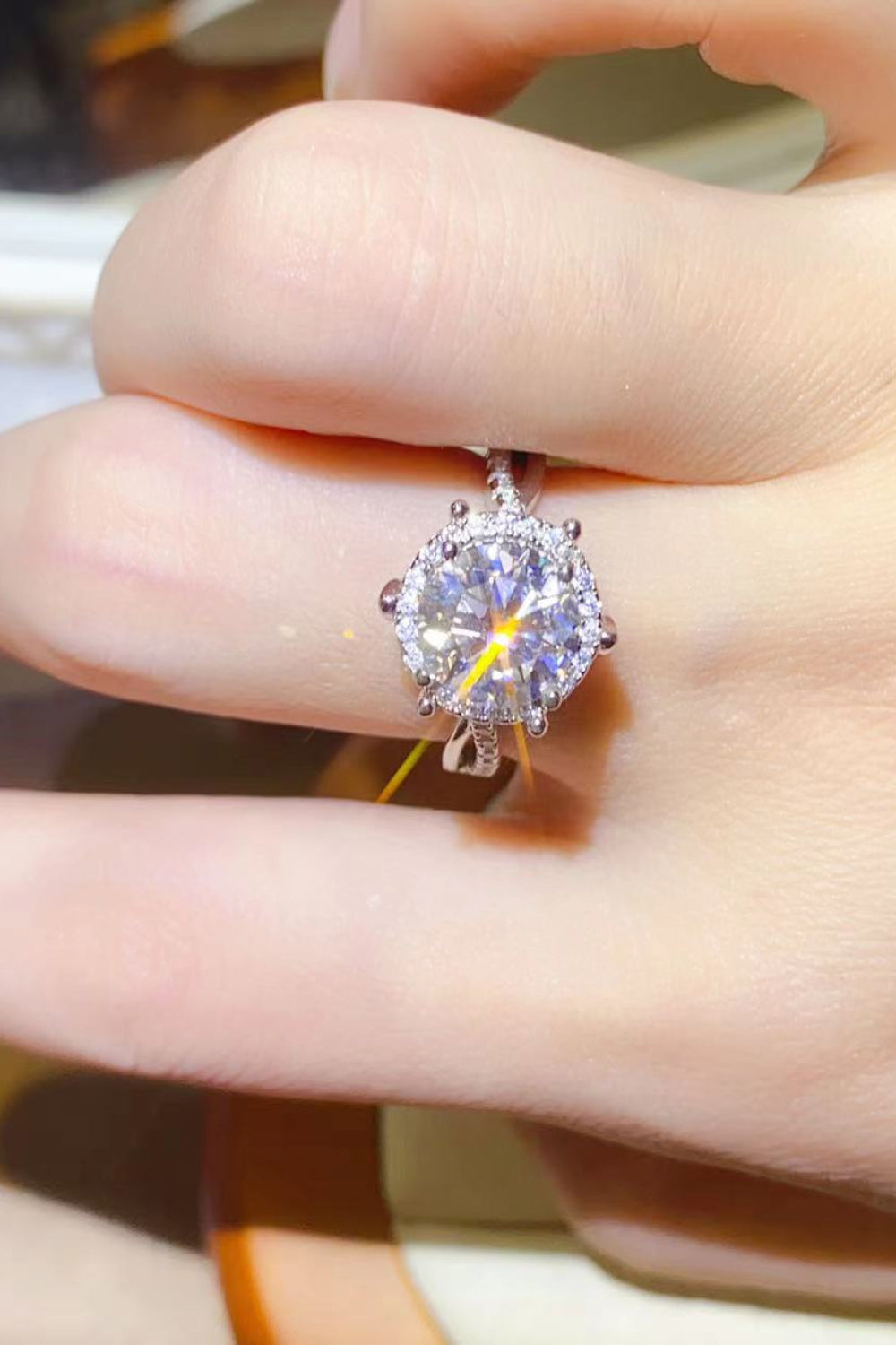 Silver halo engagement ring with moissanite center stone and diamond accents on a sterling silver band.