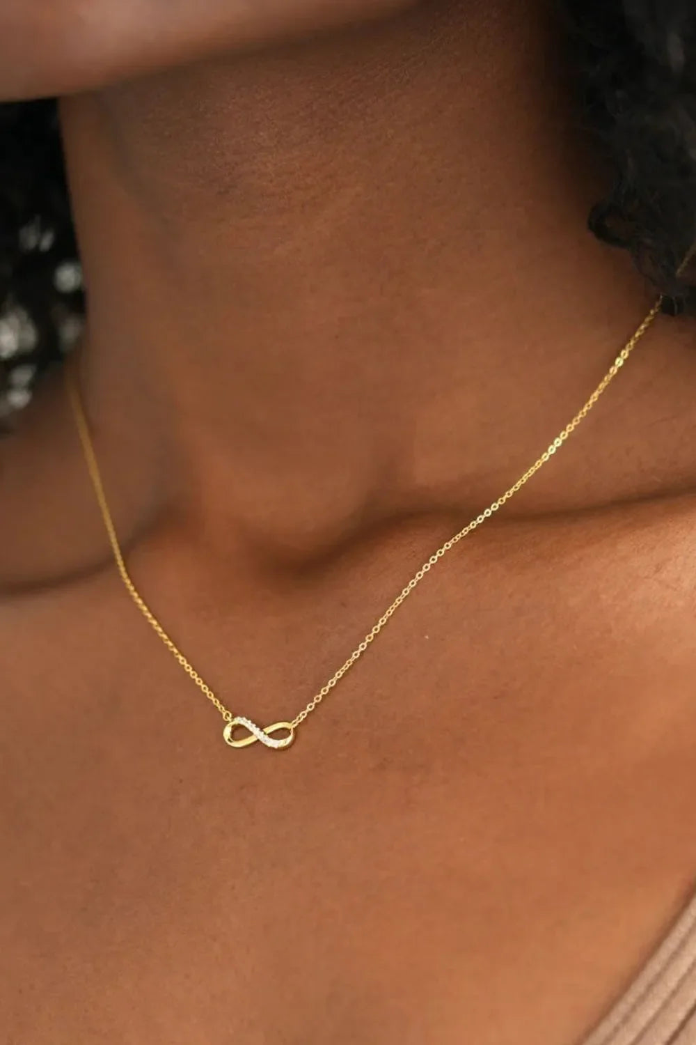 Gold infinity symbol pendant necklace with delicate pave detailing on a fine chain.