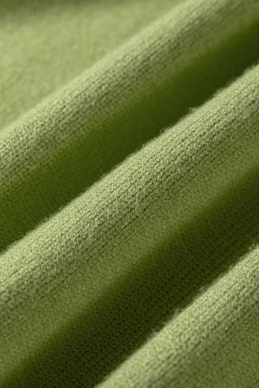 Green knit fabric with ribbed texture and soft fuzzy details.
