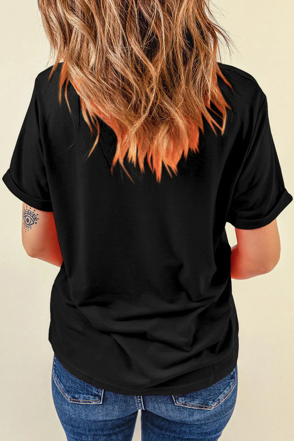 Black graphic t-shirt with rolled sleeves and an abstract eye tattoo on the arm.