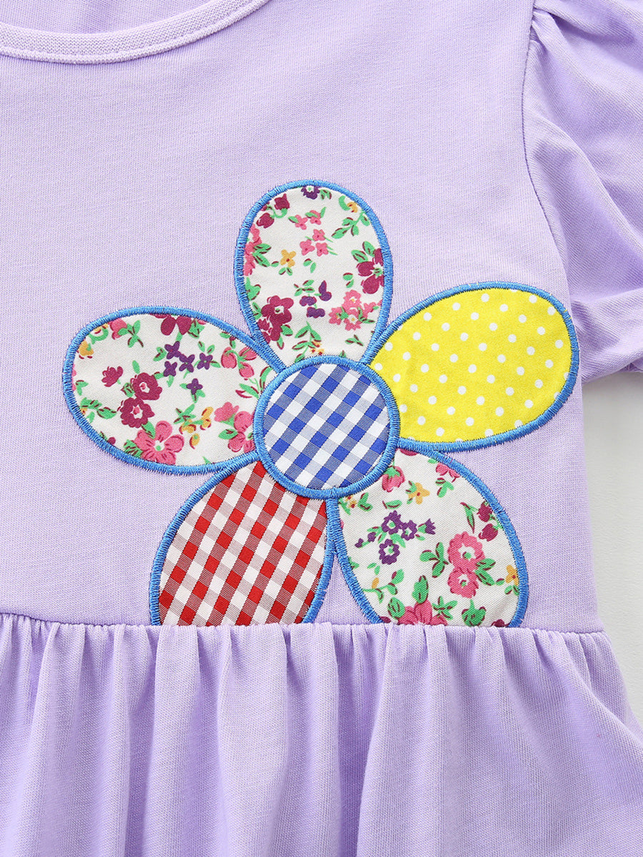 Lavender cotton toddler dress with ruffled hem and a colorful patchwork flower appliqué.