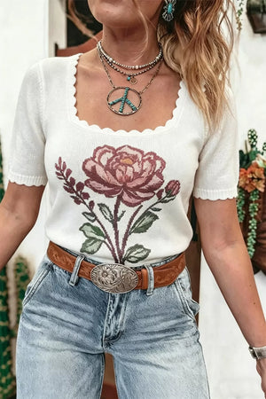 White knit top with floral embroidery and scalloped neckline.