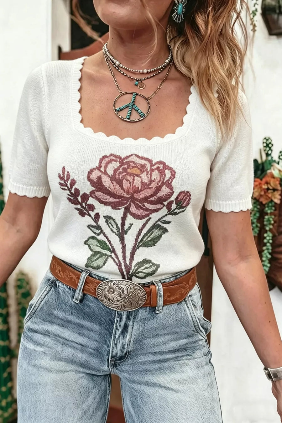 White knit top with floral embroidery and scalloped neckline.