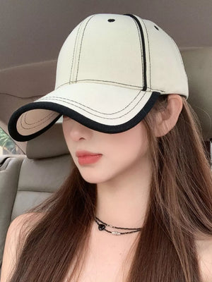 Cream white cotton baseball cap with black contrast stitching and trim.