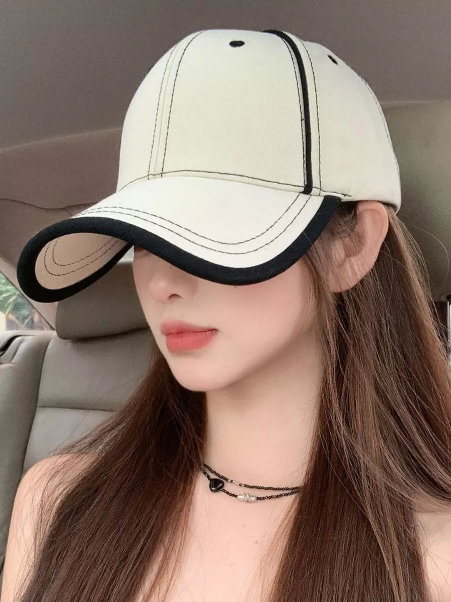 Cream white cotton baseball cap with black contrast stitching and trim.