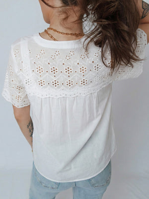 White cotton eyelet embroidered sheer shirt with short sleeves and a button-down front.