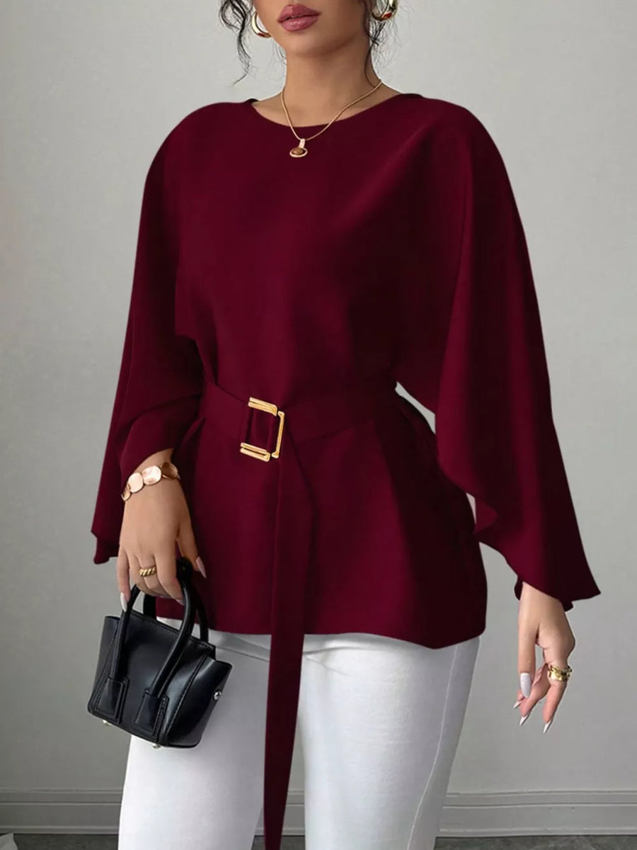 Wine red belted blouse with batwing sleeves and gold buckle detail.