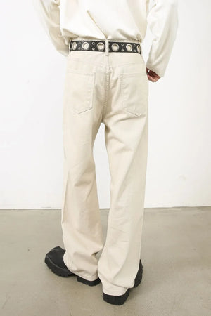 Oversized beige denim jeans with a sculpted leg and a black grommet belt.