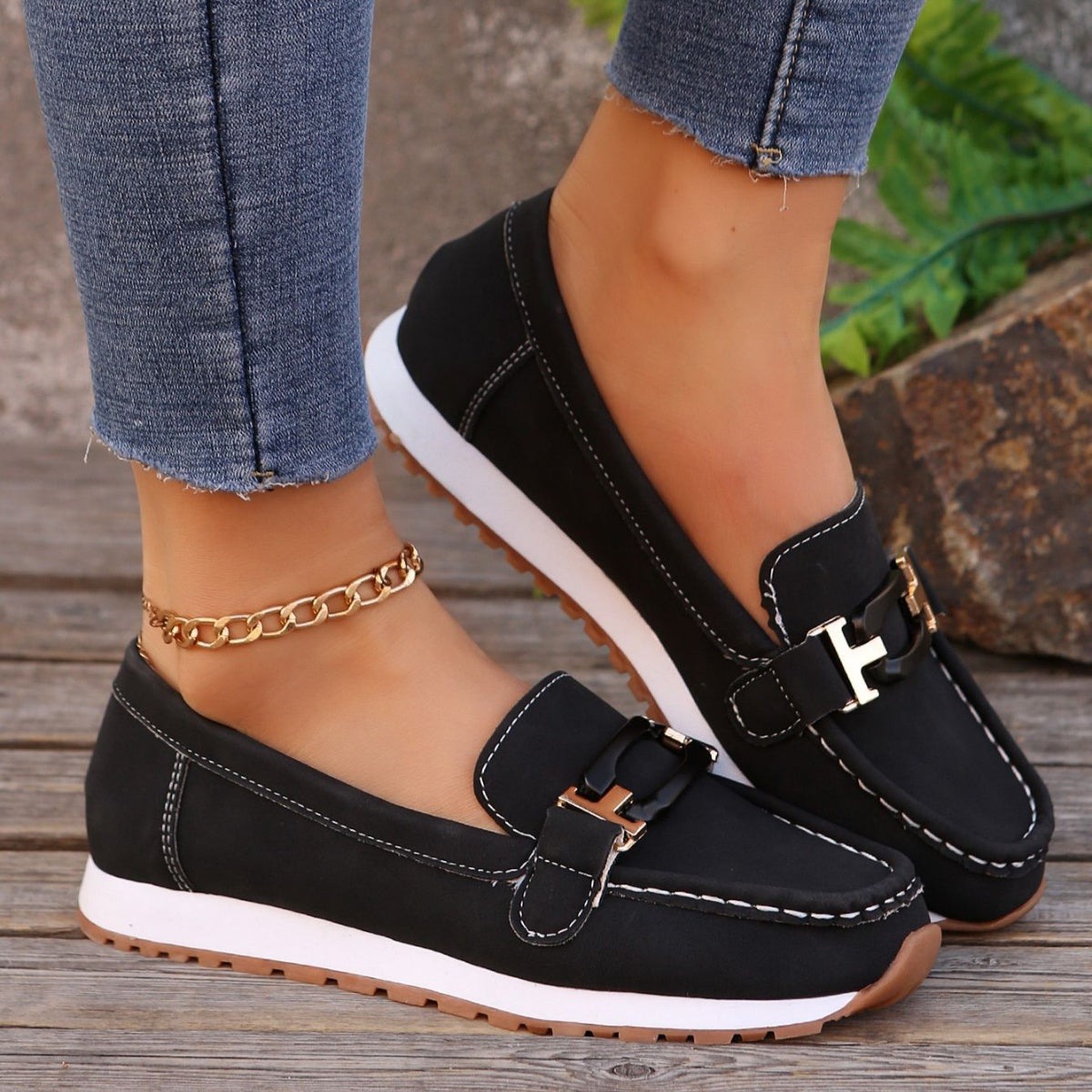 Black casual slip-on loafers with buckle detail and contrast stitching.