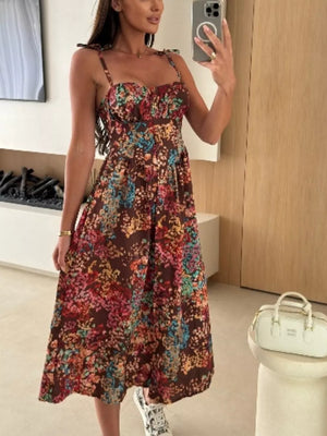Floral tie-strap midi dress in brown with a colorful floral print, sweetheart neckline, and A-line skirt.