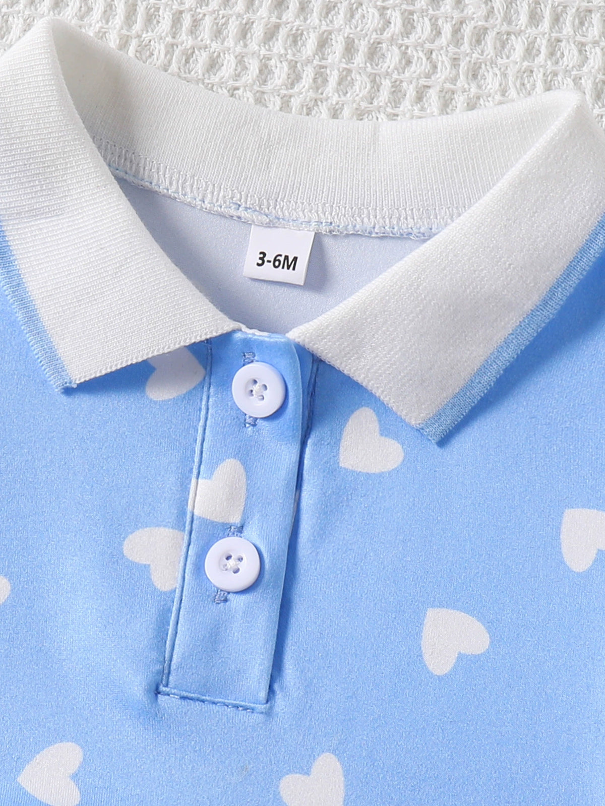 Baby dress with white heart print, blue polo collar, and button placket.
