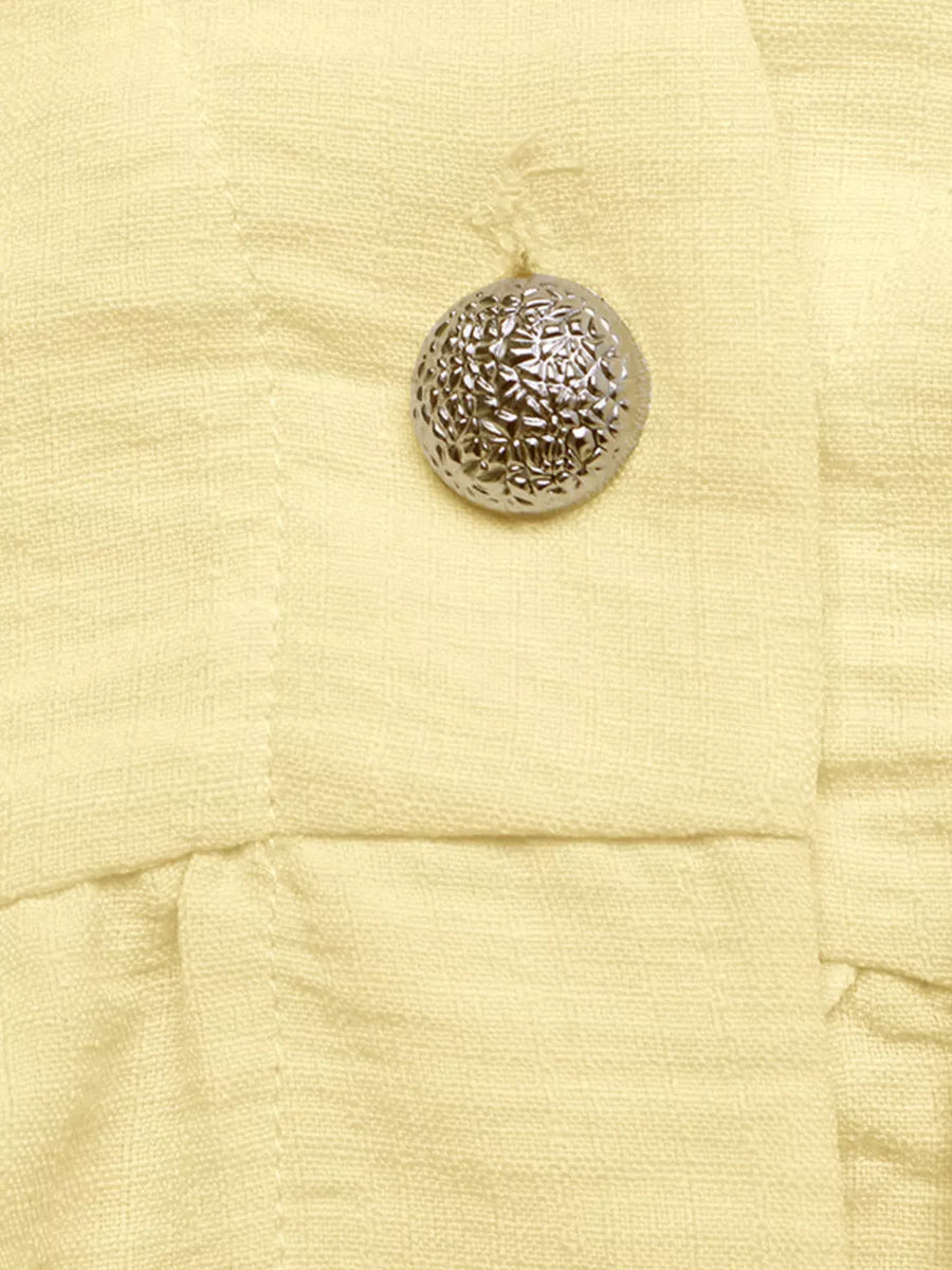 Yellow peplum hem two-piece set detail with textured silver button.