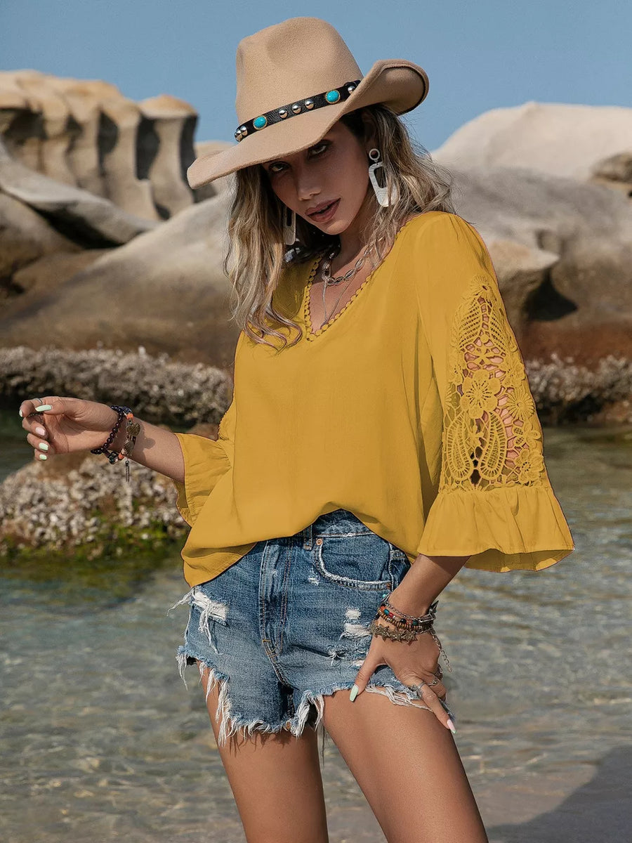 Mustard V-neck blouse with lace bell sleeves and beaded trim.