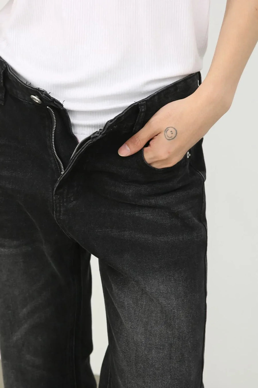 Dark wash denim trousers with exaggerated flare, shown with a hand in pocket.
