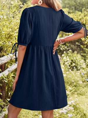 Navy puff sleeve mini dress with tie details on sleeves and a textured fabric.