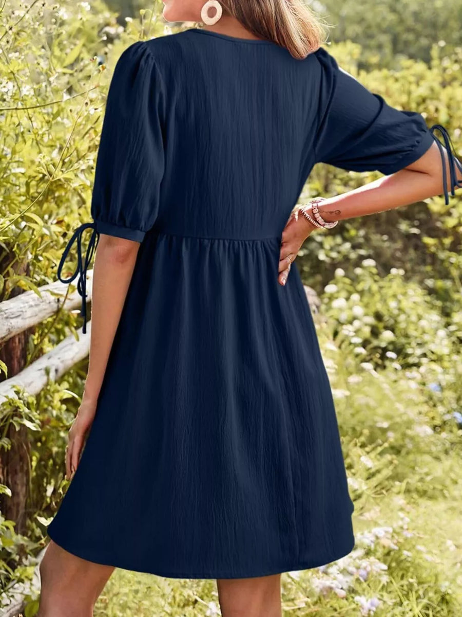 Navy puff sleeve mini dress with tie details on sleeves and a textured fabric.