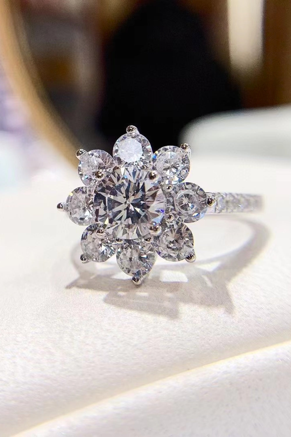 Silver moissanite engagement ring with a petal cluster design and pave band.