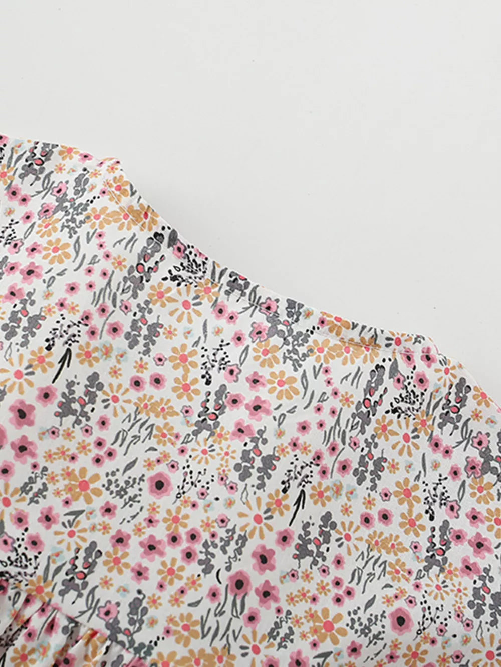 Toddler cotton dress with a whimsical floral print, ruffle sleeves, and button front detail.