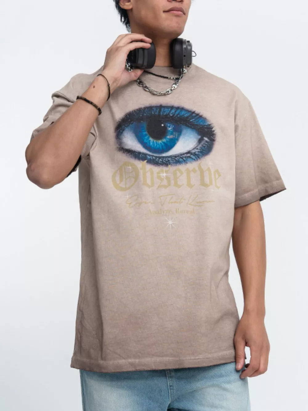 Tan graphic t-shirt with a large blue eye print and text.